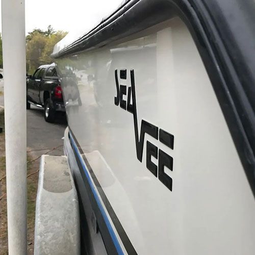 Sea Vee boat with black lettering on white side, parked by a truck.