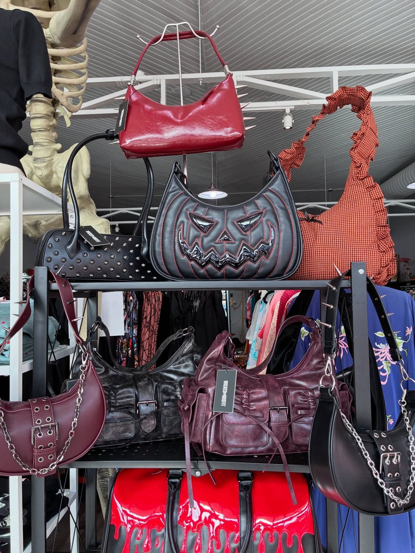 Bags on shelves in a store, various styles and colors, including a pumpkin design