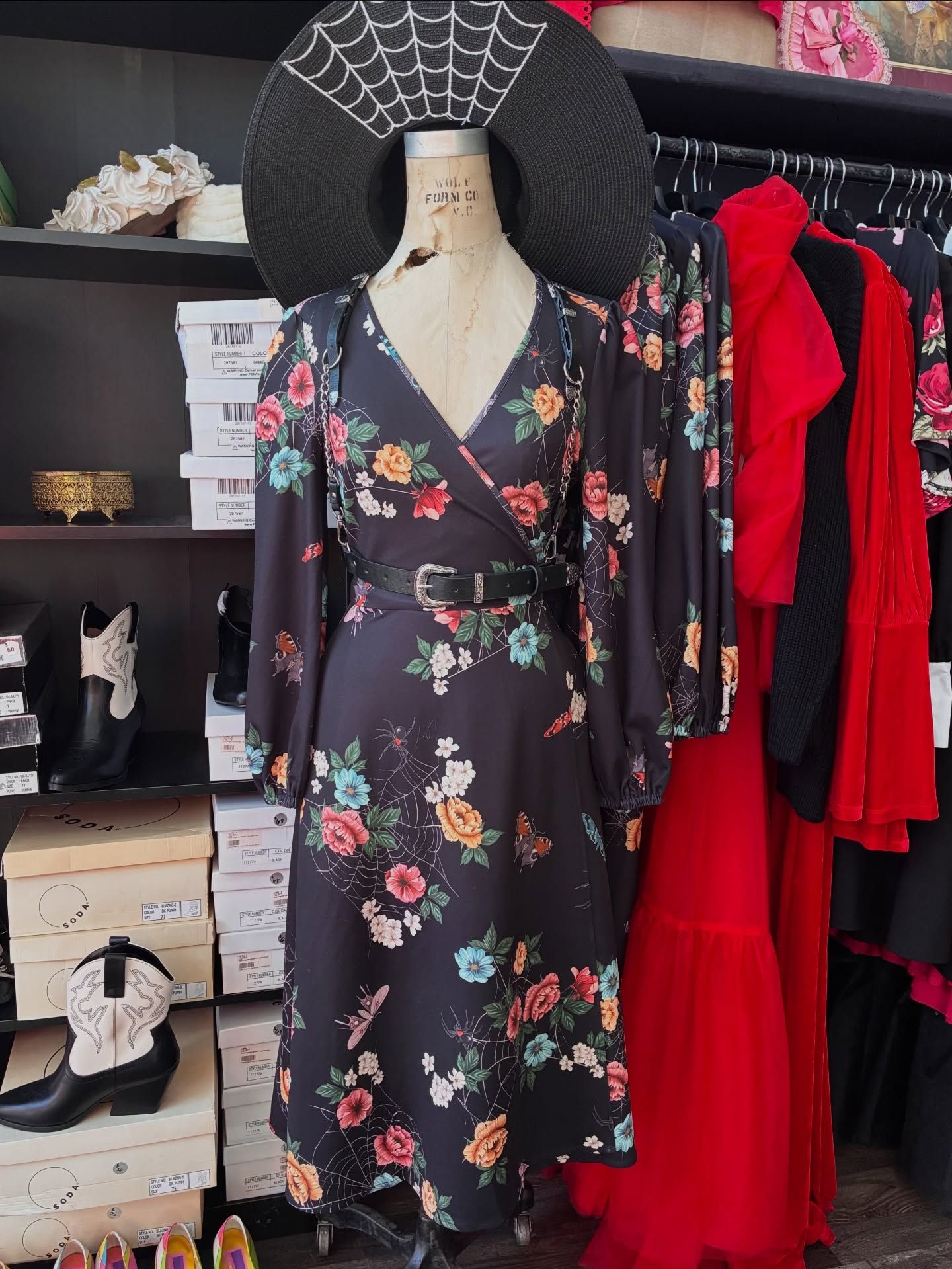 Floral wrap dress on a mannequin, with a large black hat