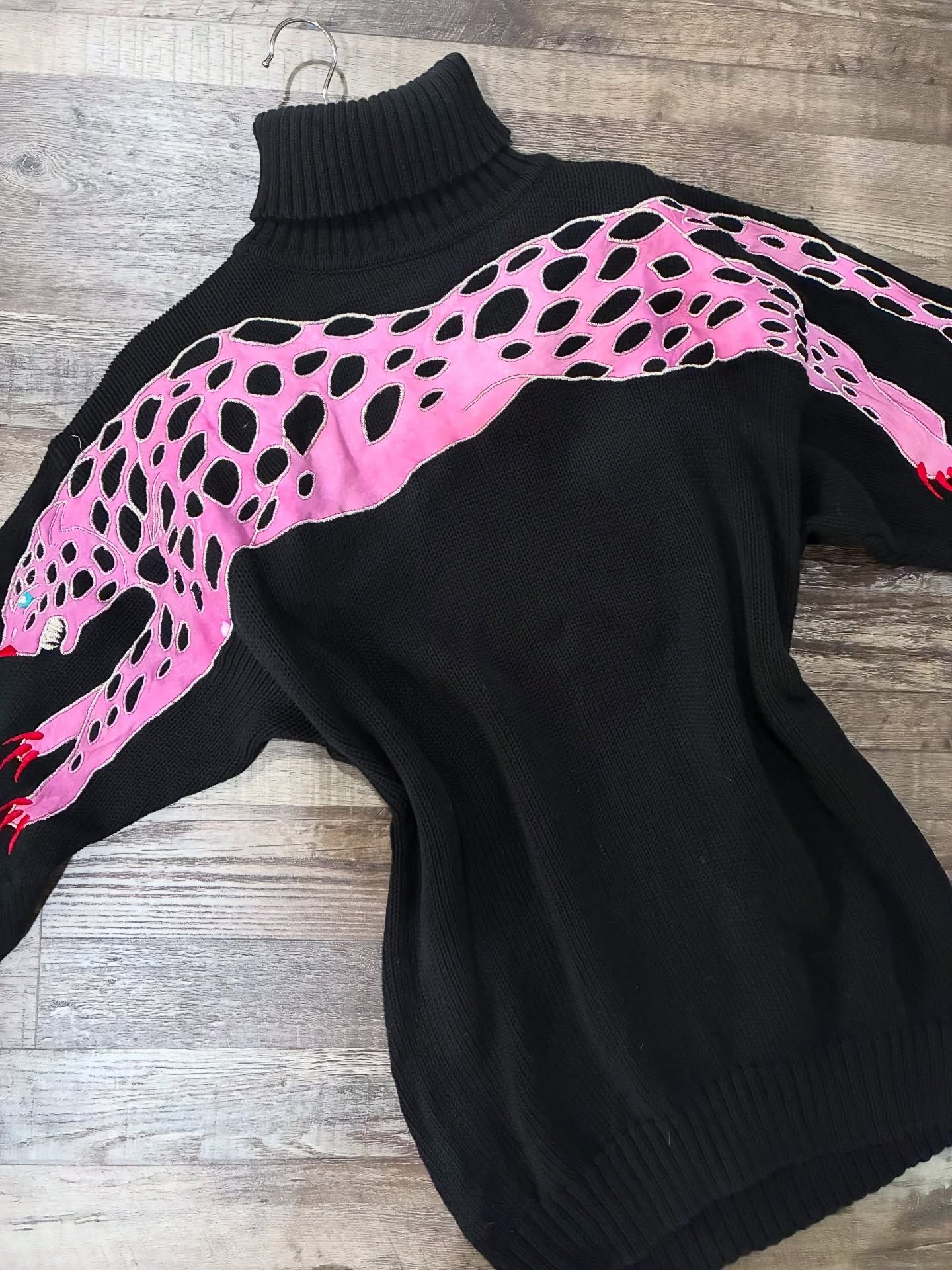 Black turtleneck sweater with a pink and black leopard design across the chest and sleeves