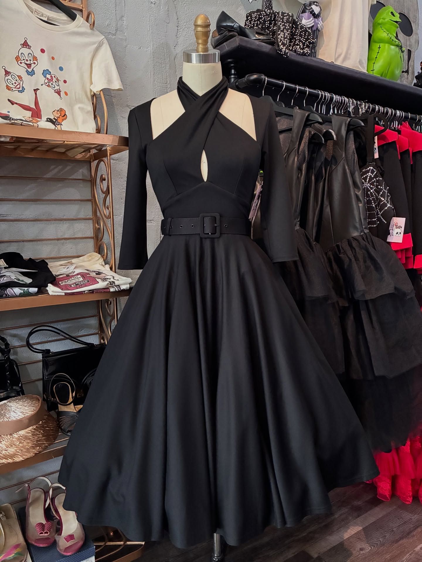 Black halter dress on a mannequin; full skirt, mid-sleeves, belted waist