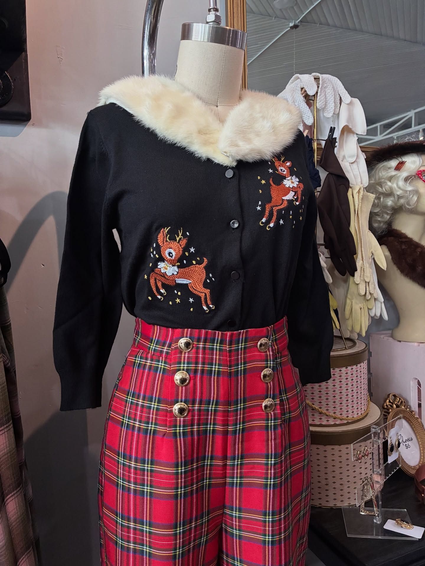 Black cardigan with reindeer, fur collar, red plaid pants with gold buttons, displayed on a mannequin