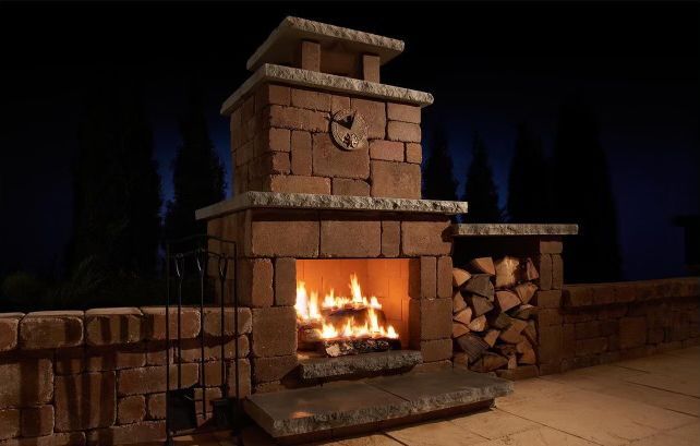 A fireplace with a clock on top of it is lit up at night