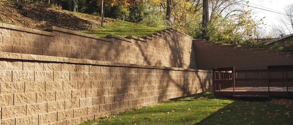 A large brick wall is surrounded by grass and trees in a backyard