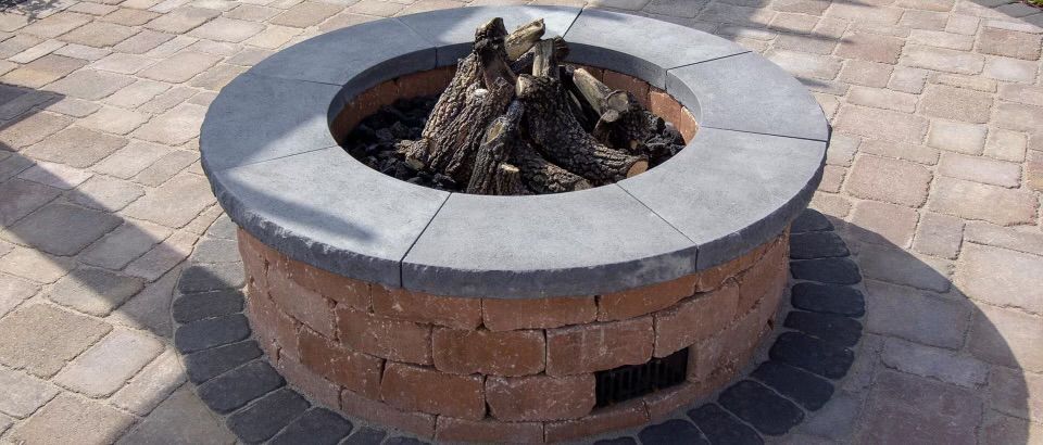 A fire pit is sitting on top of a brick patio