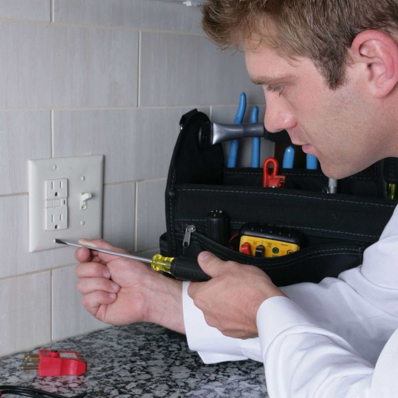 a man is holding a screwdriver in front of a light switch