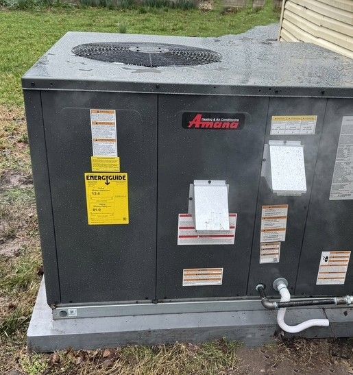 Outdoor Amana HVAC unit on a concrete pad beside a building wall.