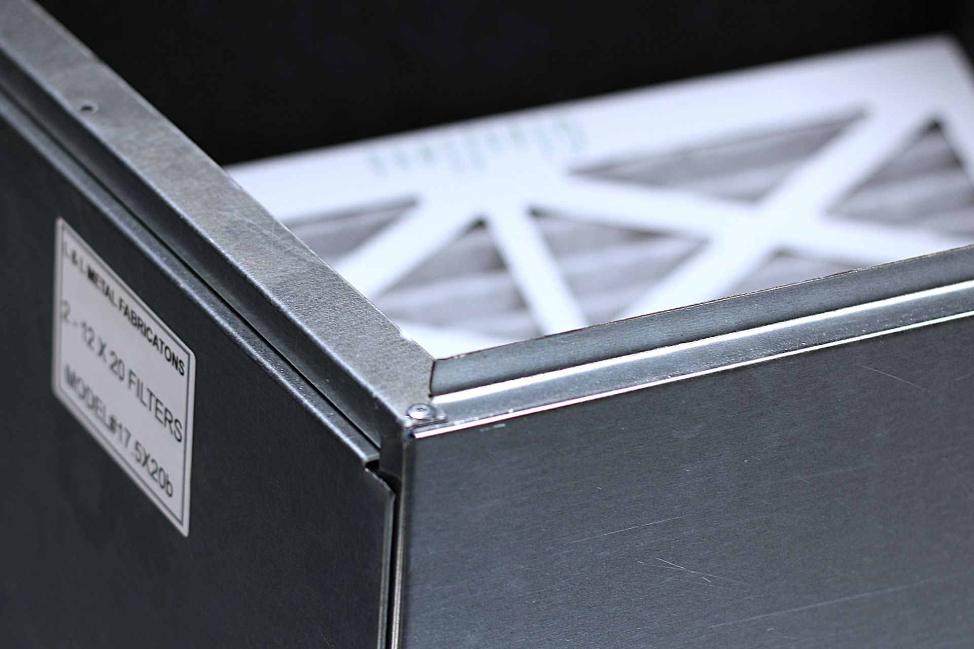 Close-up of a black metal box with a white label and a white lattice top.