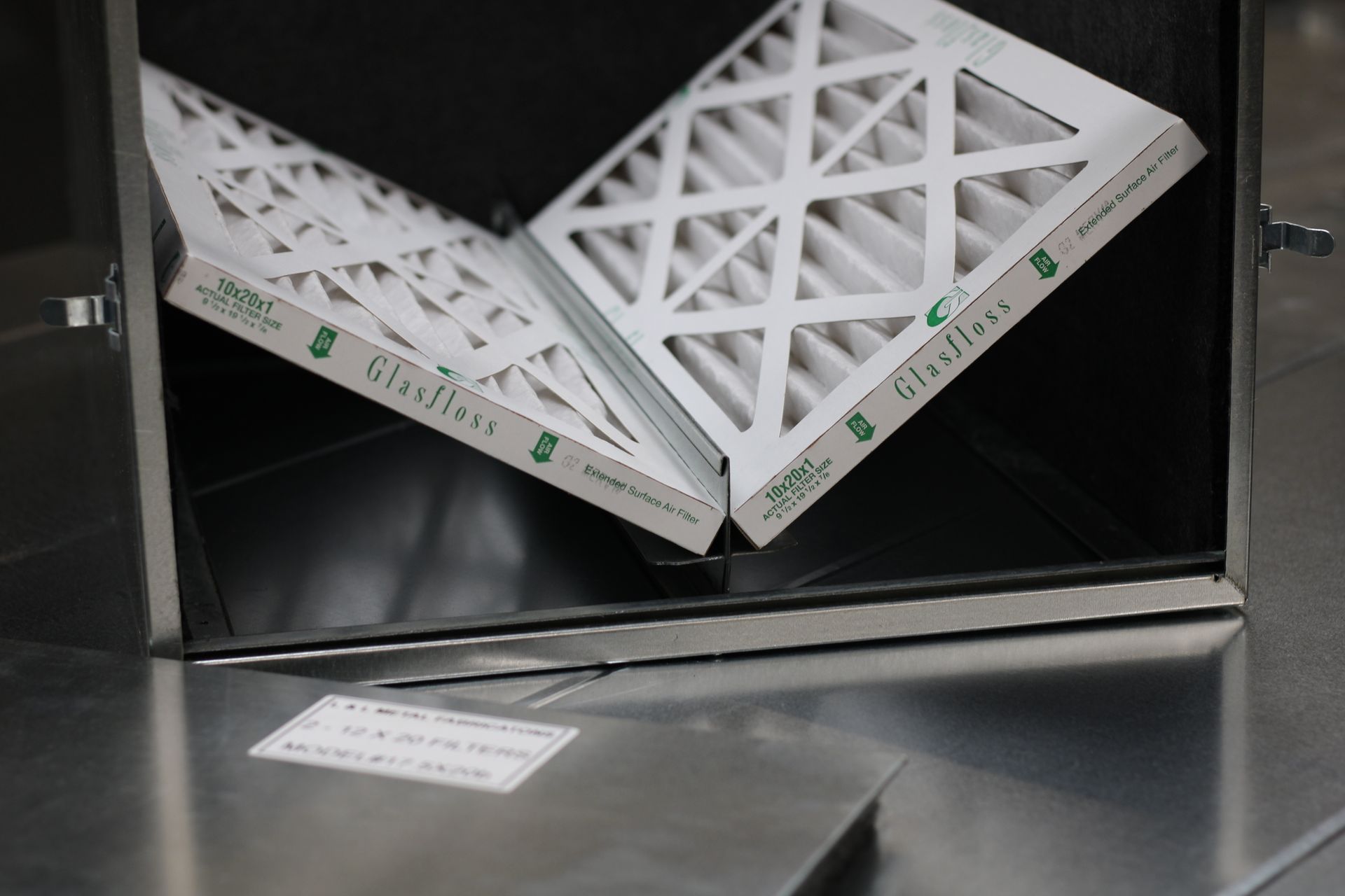 White triangular air filters stacked inside a metal HVAC unit.