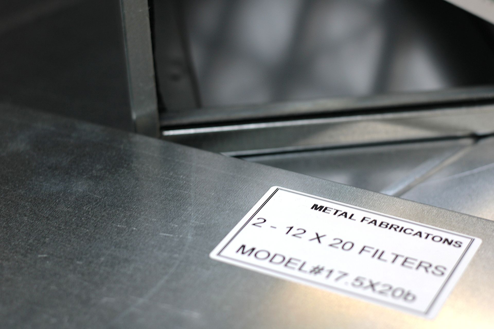 Close-up of a metal filtration label on a gray machine.
