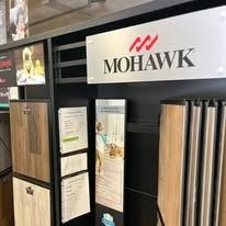 Mohawk flooring display in a store, featuring samples, signage with the brand's logo, and wood flooring.
