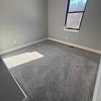 Empty room with new gray carpet and a window on the wall. The room's walls are painted gray.