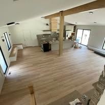 Spacious, open-plan interior with light wood floors and white walls.