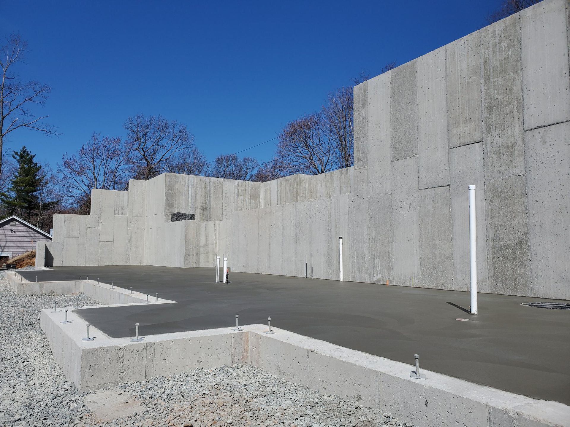 Concrete foundation and walls under construction on a sunny day.