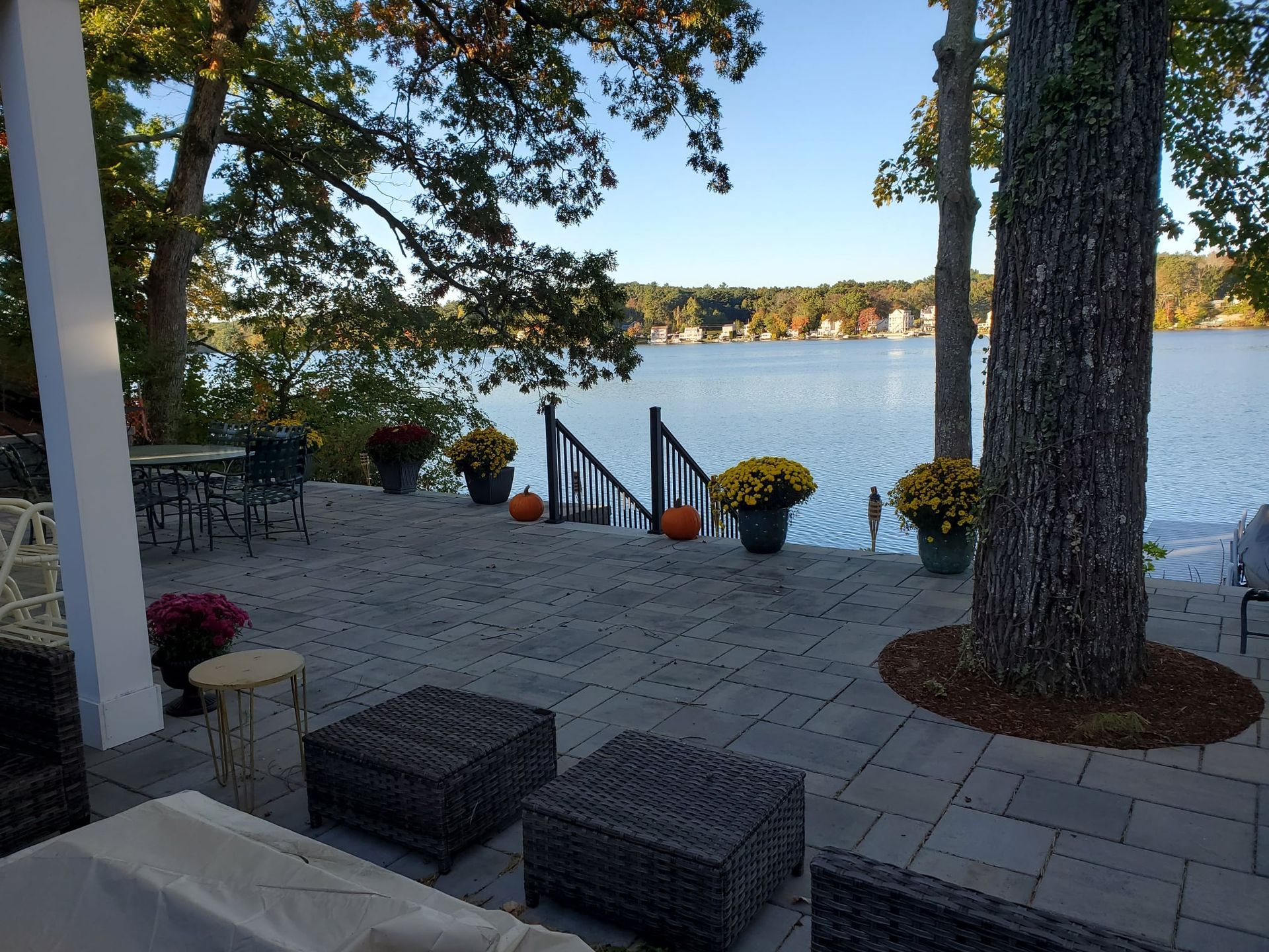 Patio overlooking a lake with seating, trees, and fall decorations.