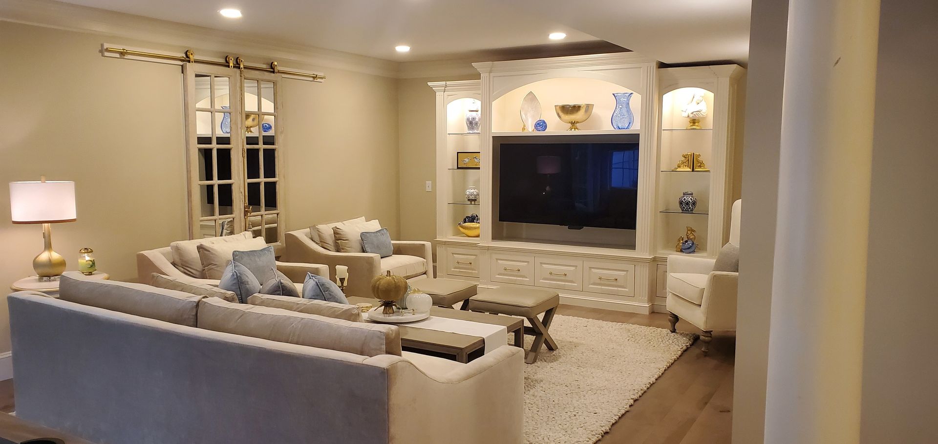 Living room with white furniture, entertainment center, and a large area rug.