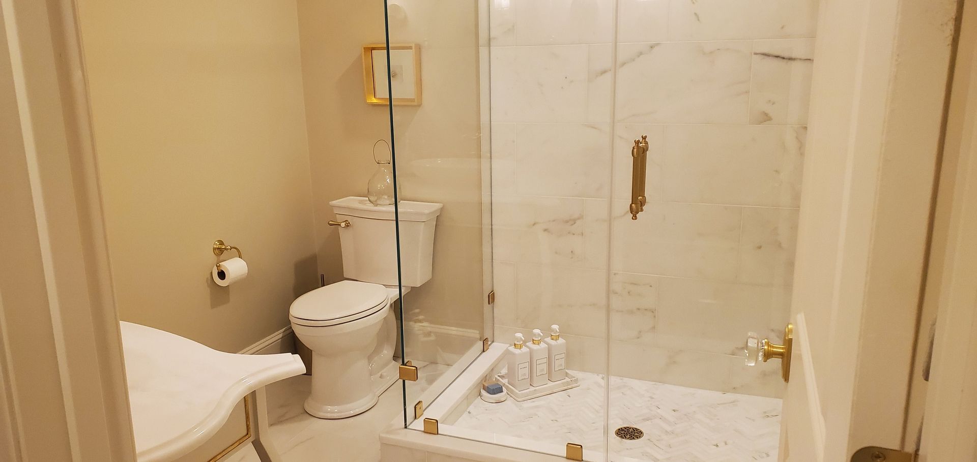 Bathroom with white toilet, shower, and marble tile. The walls are a light beige.