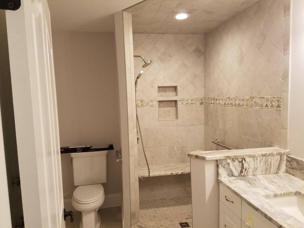 Bathroom with a tiled shower, toilet, and vanity. Light gray walls, white cabinets, and granite countertop.