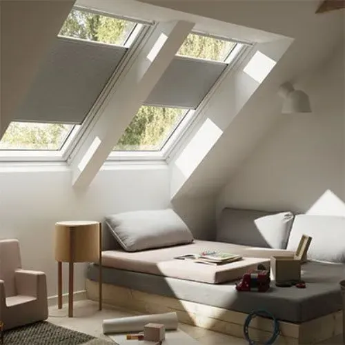 Minimal attic bedroom with slanted skylight windows, low bed, and neutral decor