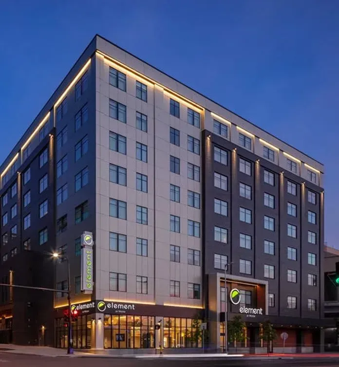 Modern multi-story Element hotel at dusk with illuminated windows and street-level storefronts