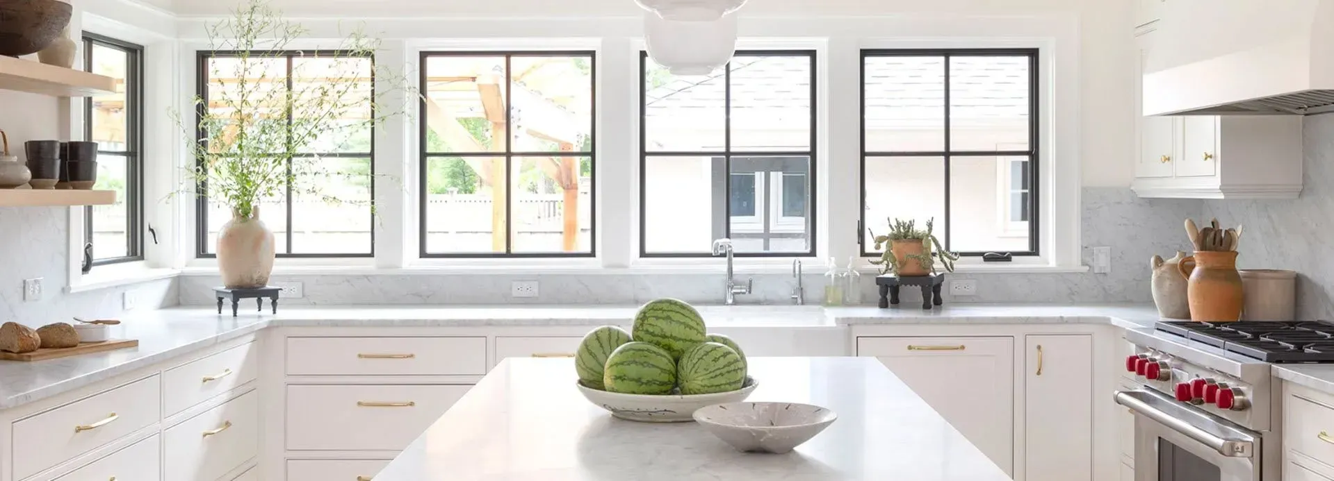 Bright white kitchen with large windows, white cabinets, and a green cabbage centerpiece on the island