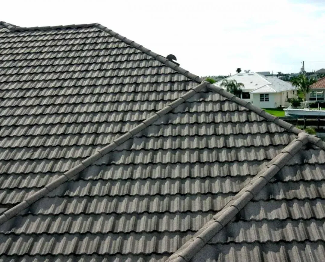 Gray tiled rooftops with diagonal beams in a suburban neighborhood under a cloudy sky