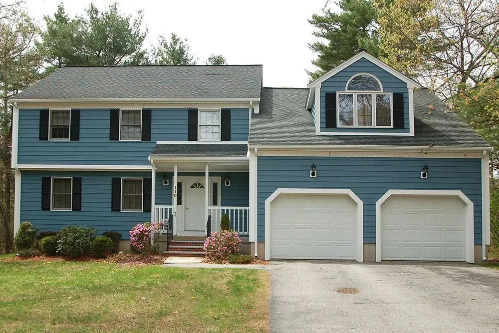 Blue two-story suburban house with white trim, front porch, and two-car garage on a driveway
