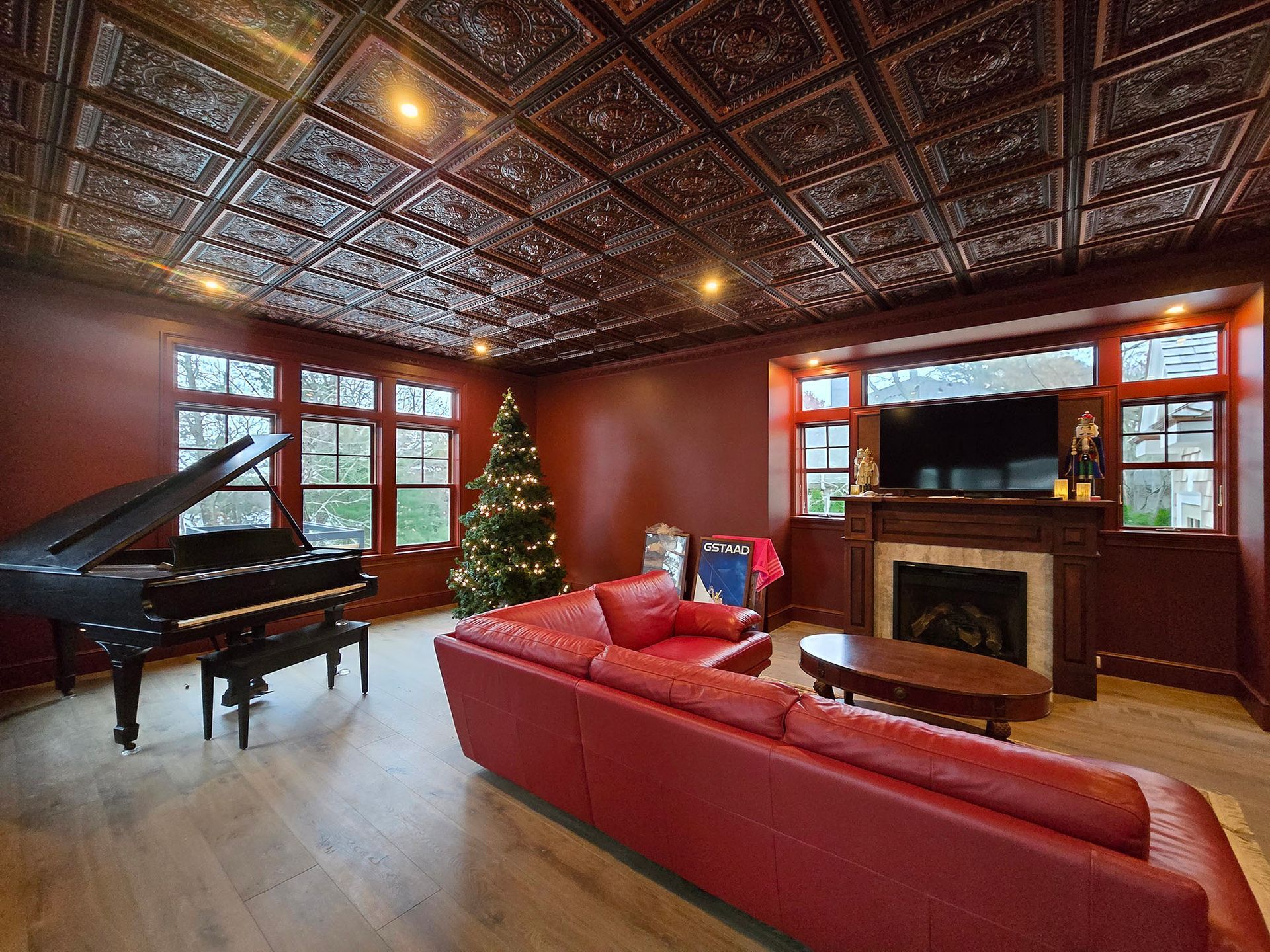 Elegant living room with red sofa, grand piano, Christmas tree, and ornate ceiling