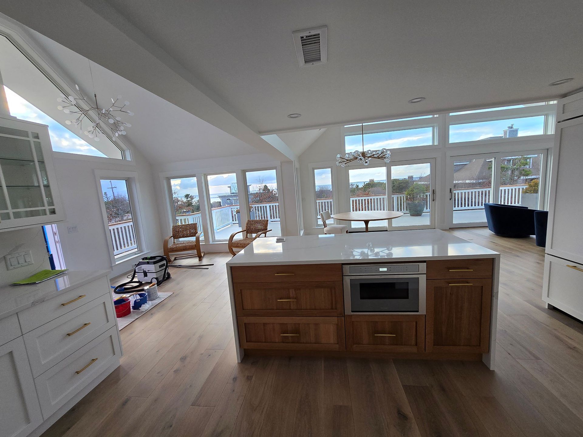 Bright open kitchen with a central island, wood floors, and large windows overlooking snowy outdoors