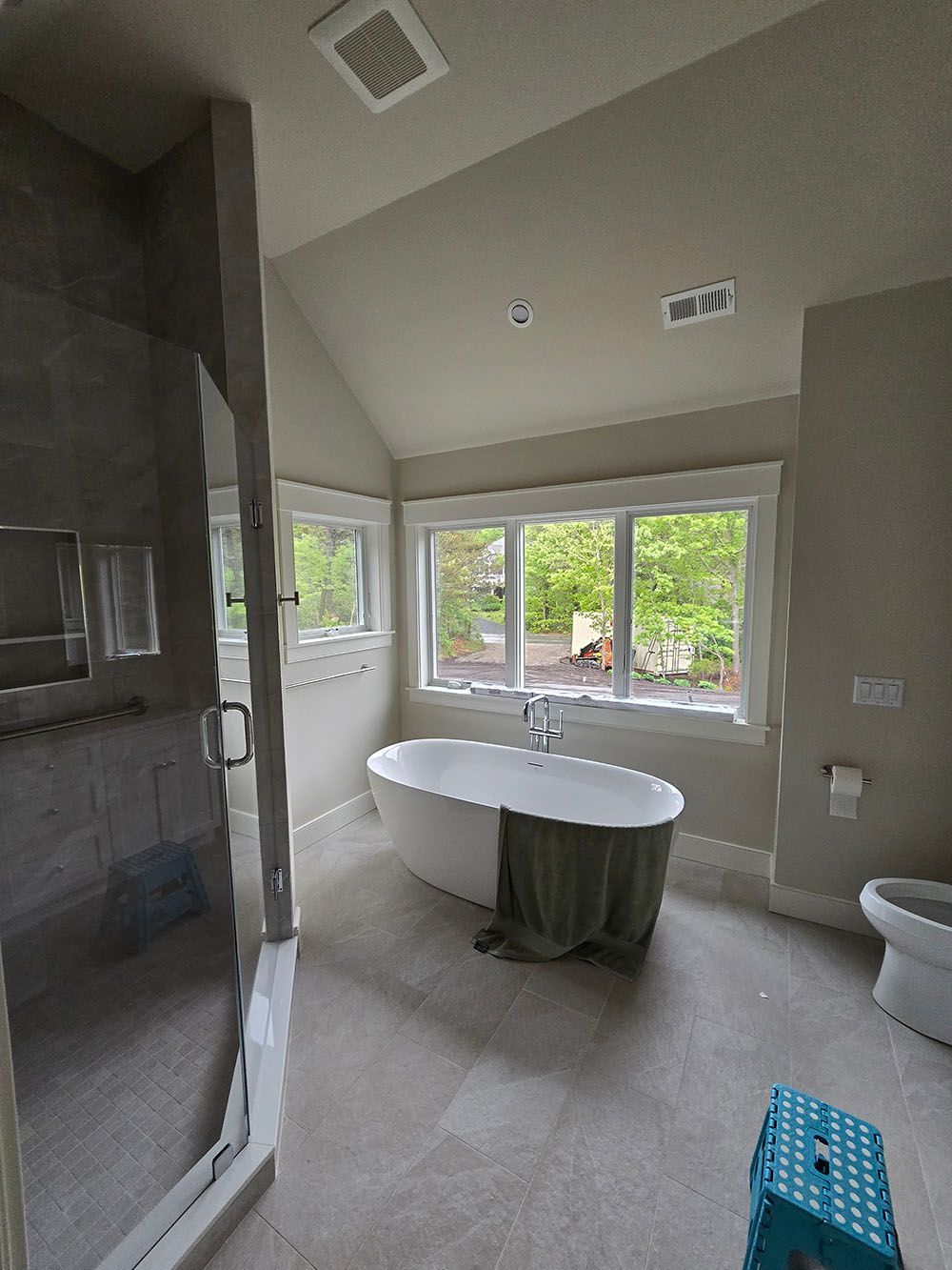 Modern bathroom with freestanding tub, large windows, shower, and gray tile flooring
