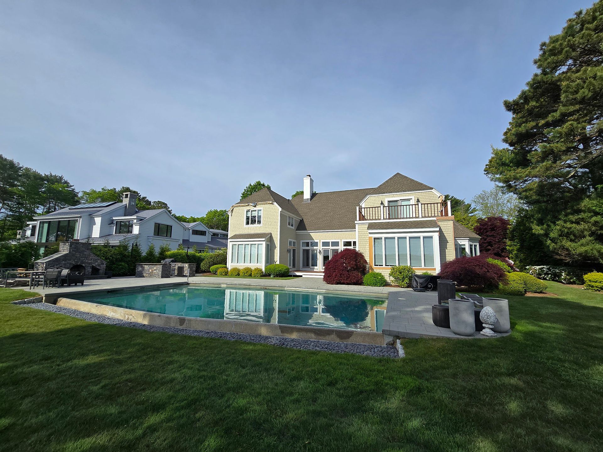 Large suburban house with a swimming pool and manicured lawn in a sunny backyard