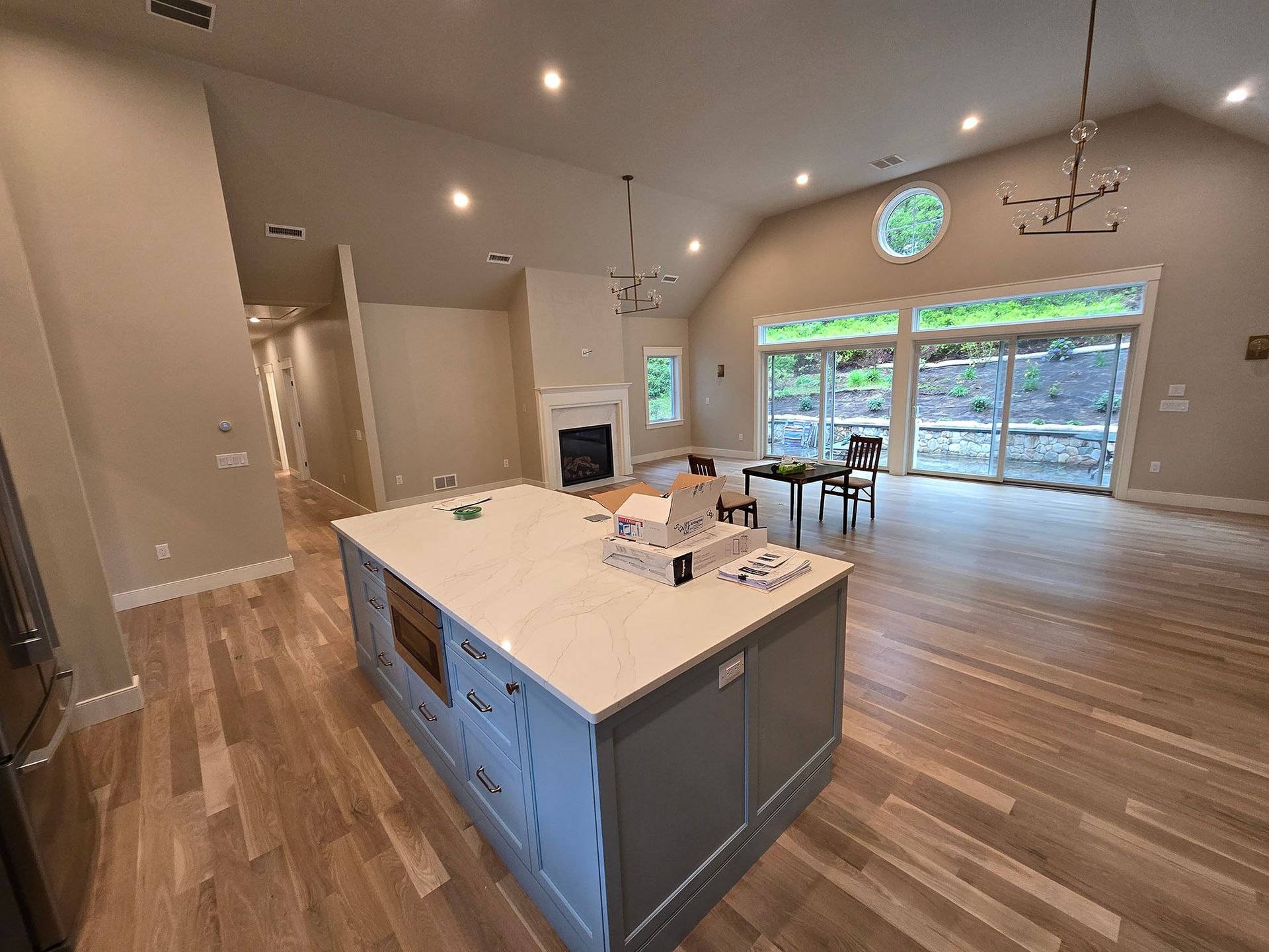 Spacious modern kitchen and dining area with island, wood floors, and large sliding glass doors.