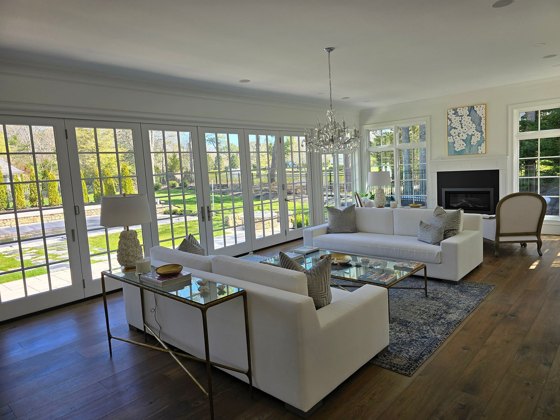 Bright modern living room with white sofas, large windows, and a patterned rug.
