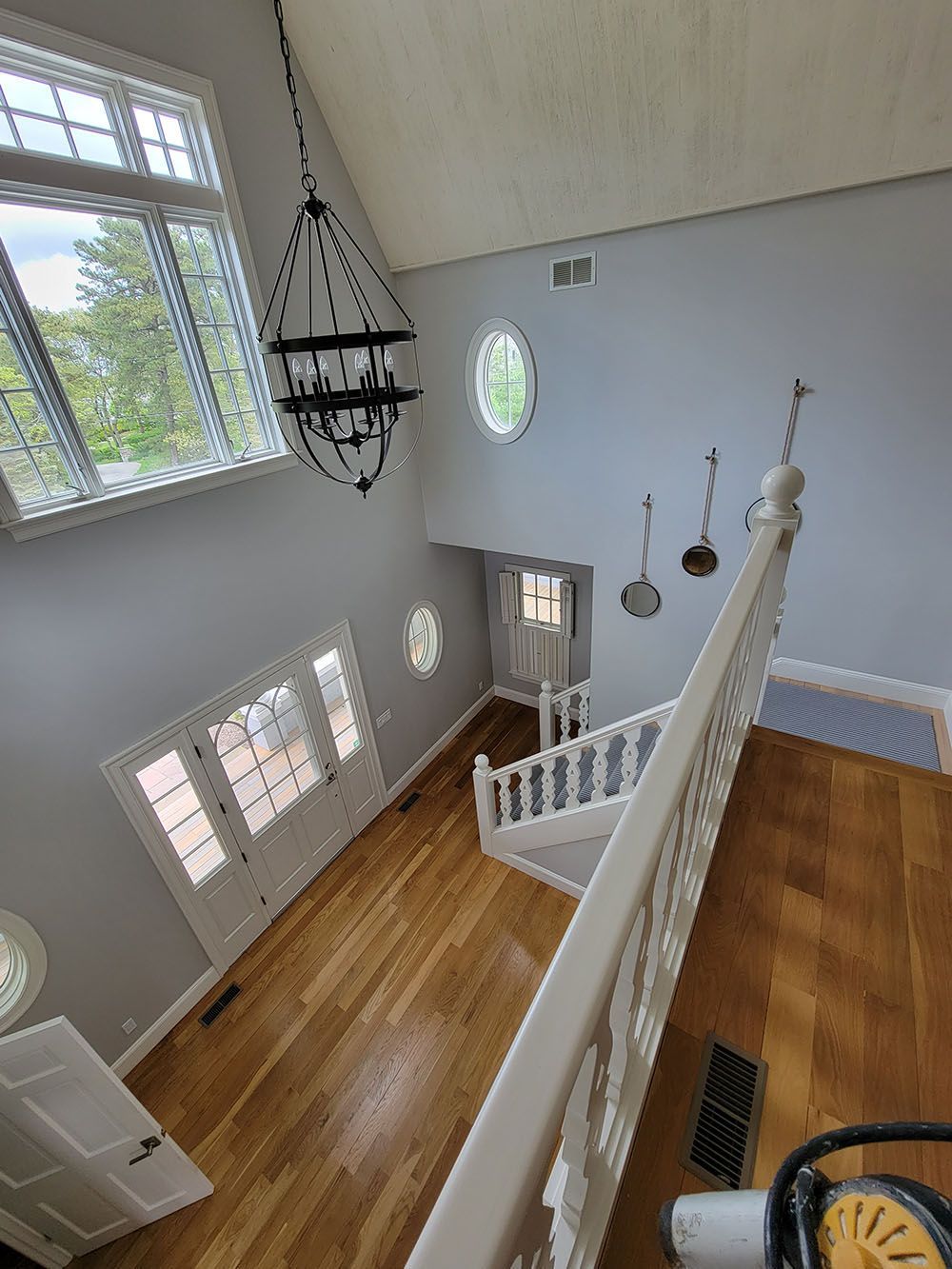 Spacious foyer with hardwood floors, chandelier, staircase, and large windows overlooking the entry below