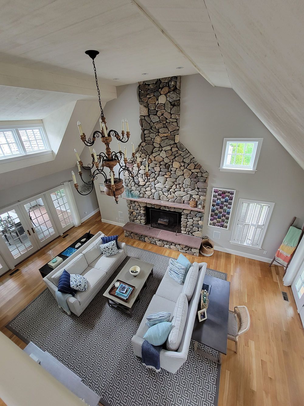 Large living room with vaulted ceiling, stone fireplace, chandelier, and sectional seating around a coffee table.