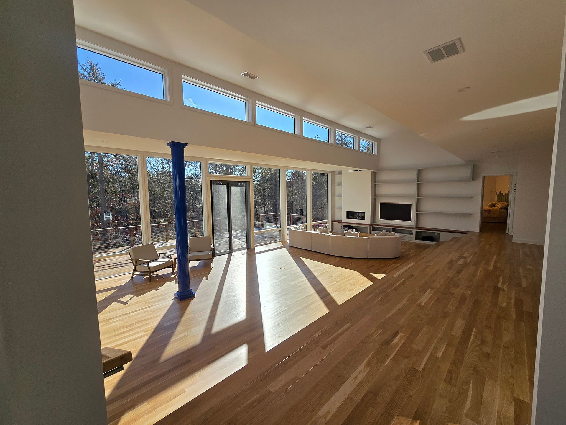 Bright modern living room with wood floors, large windows, and a sectional sofa by the patio doors