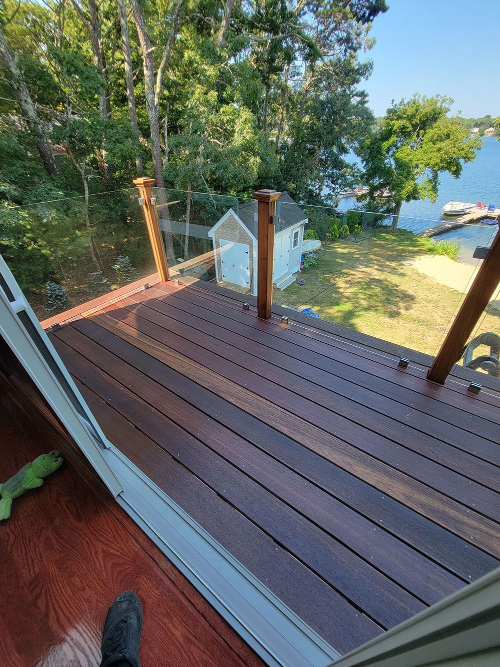 Wooden deck with posts overlooking trees and a bright blue ocean view