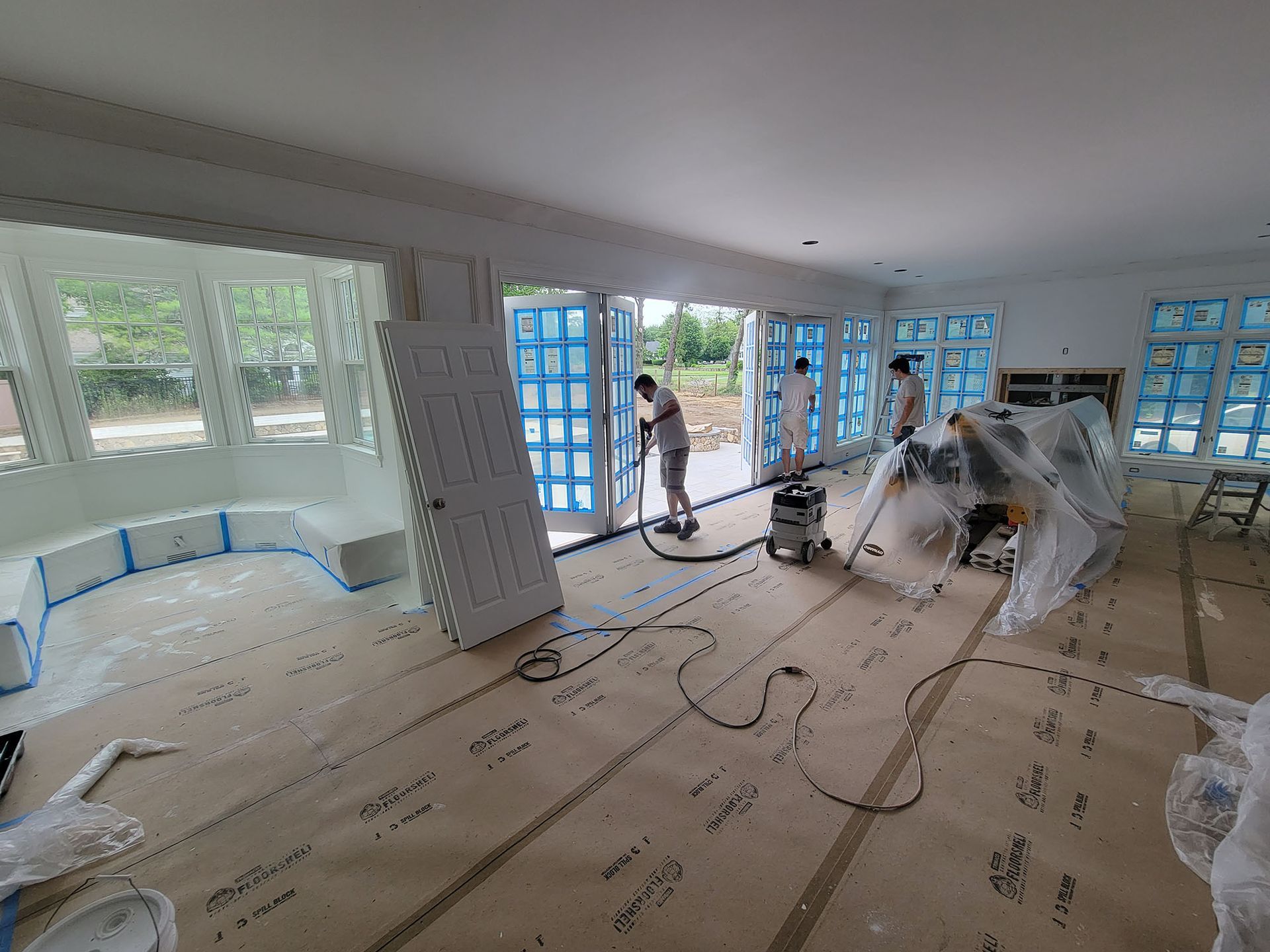 Workers sanding a bright living room floor during home renovation
