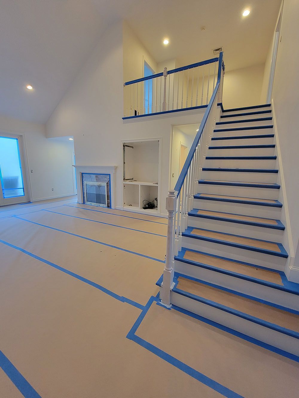 Bright stairwell with blue tape markings on the floor and stairs in a white interior room.