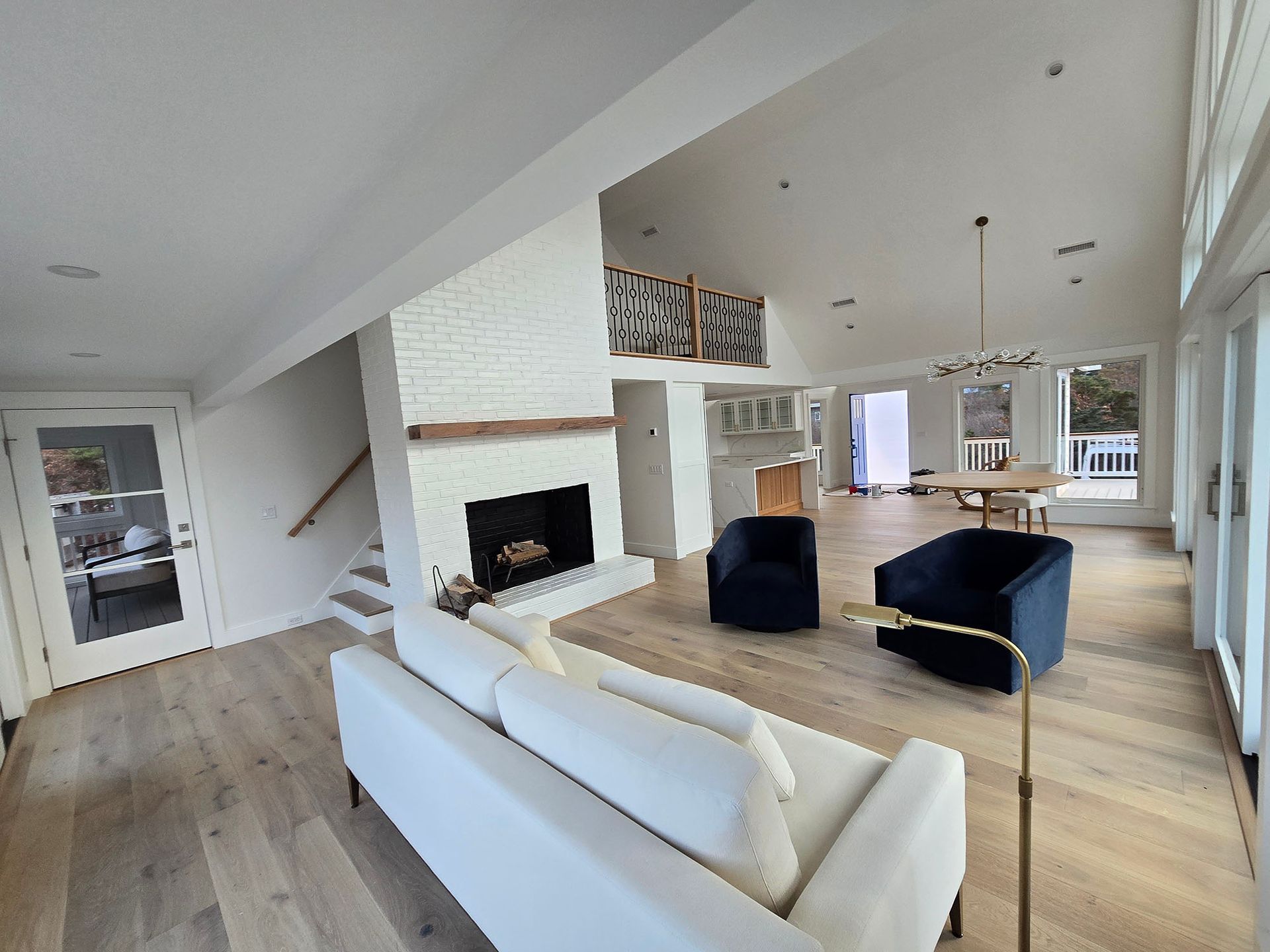 Bright modern living room with white sofa, blue chairs, fireplace, and large windows