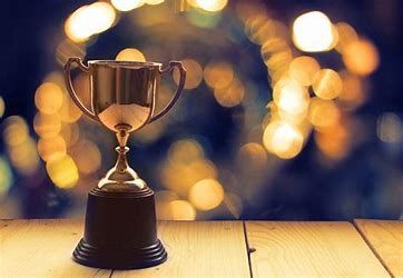 Gold trophy on a wooden surface with a blurred background of golden bokeh lights.