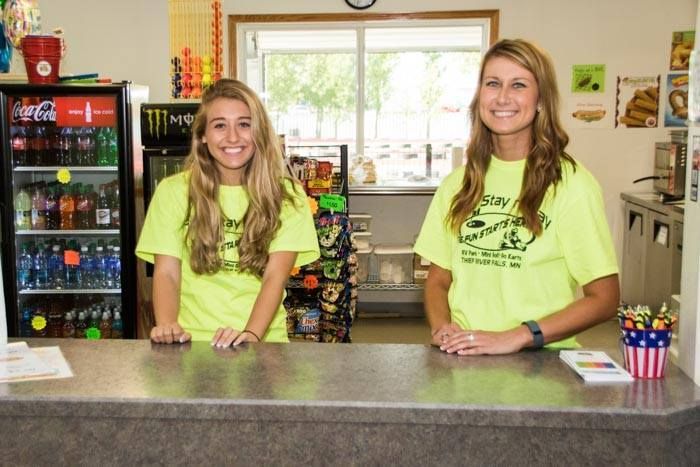 Two women wearing neon yellow shirts are standing at a counter