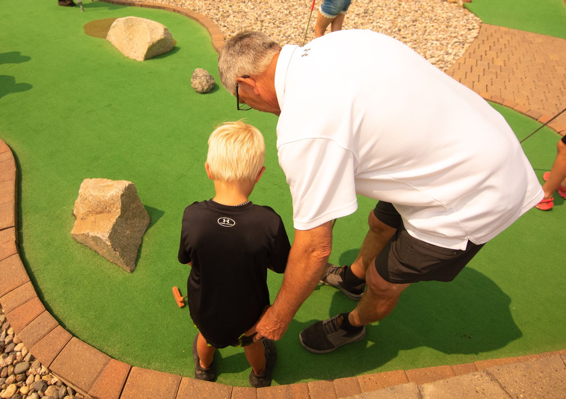 A man and a boy are playing a game of mini golf