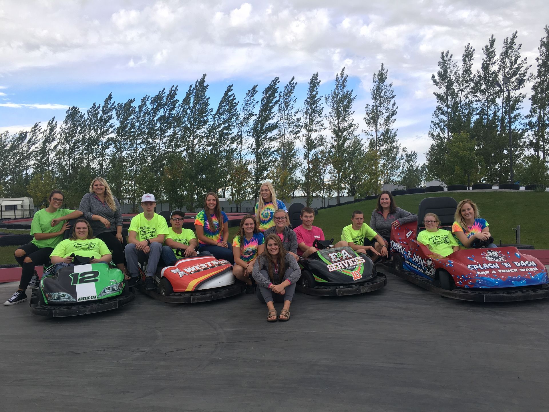 A group of people are posing for a picture while sitting on go karts.