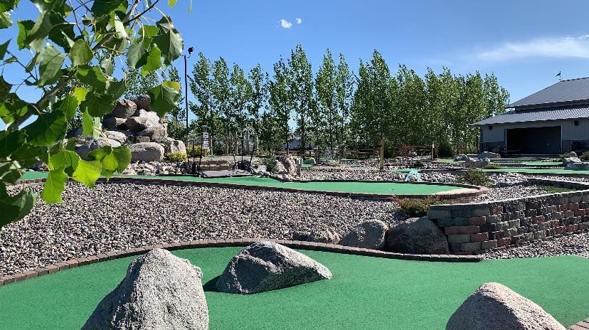 A golf course with rocks and trees in the background.