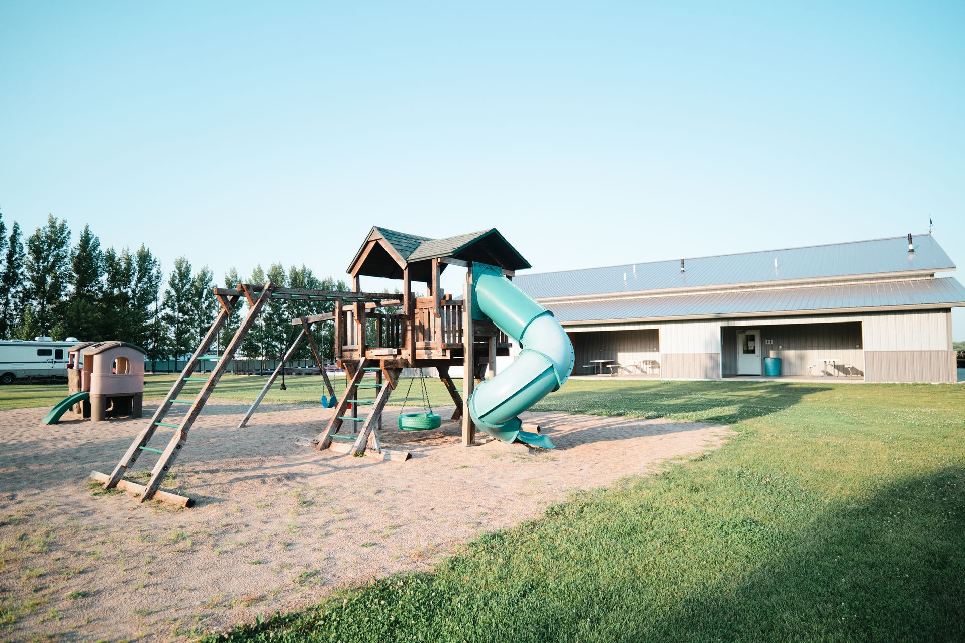 A playground with a slide and swings in front of a building.