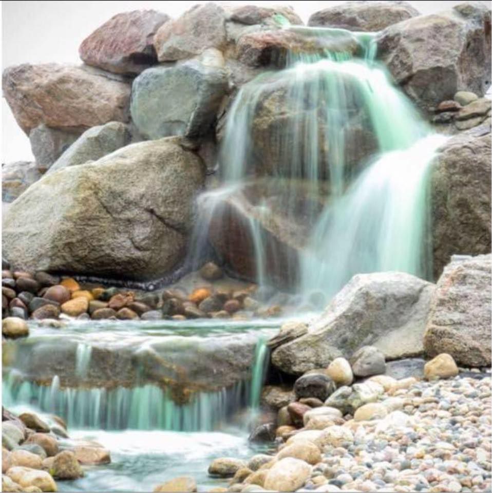 A waterfall is surrounded by rocks and a stream