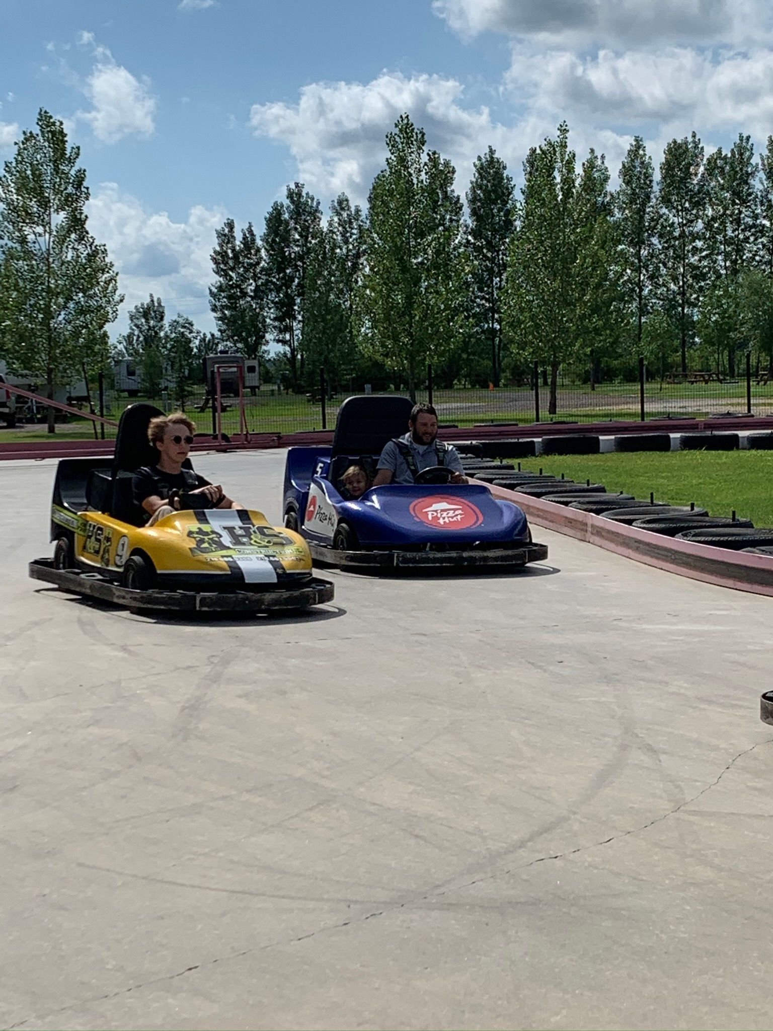 Two people are riding go karts on a track.