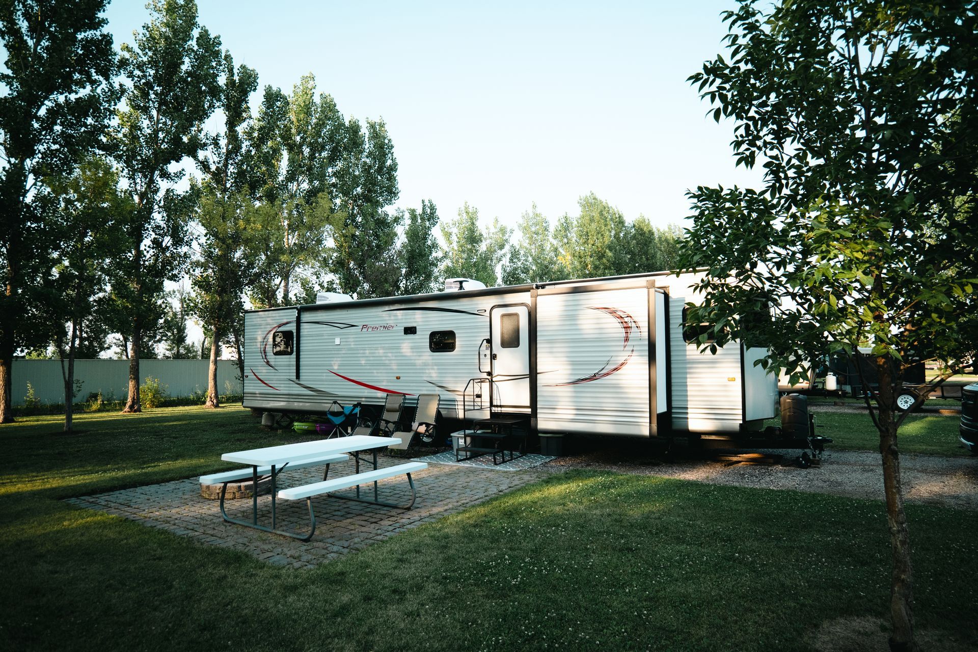 A rv is parked in a grassy area with a picnic table.
