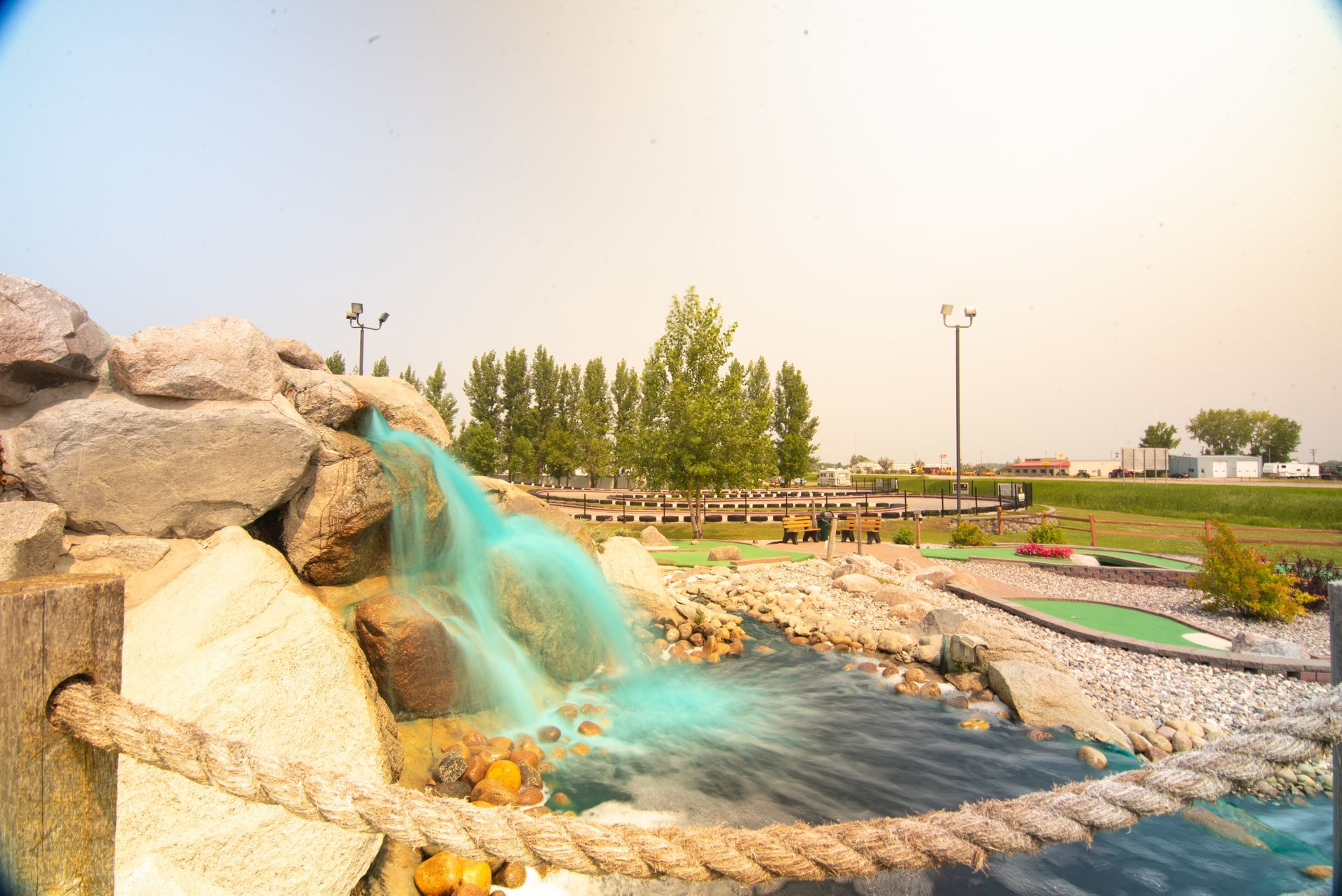 A waterfall is surrounded by rocks and trees in a park.